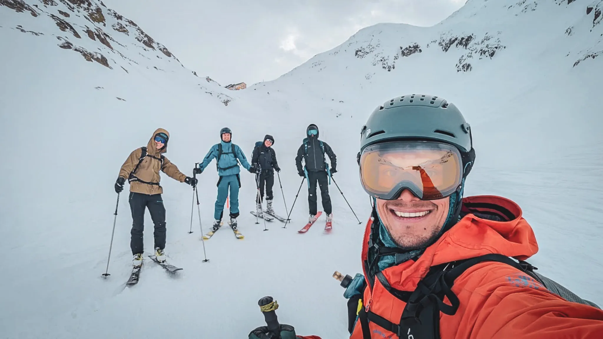 Groupe de skieurs souriants dans un décor alpin enneigé au col du Grand-Saint-Bernard.