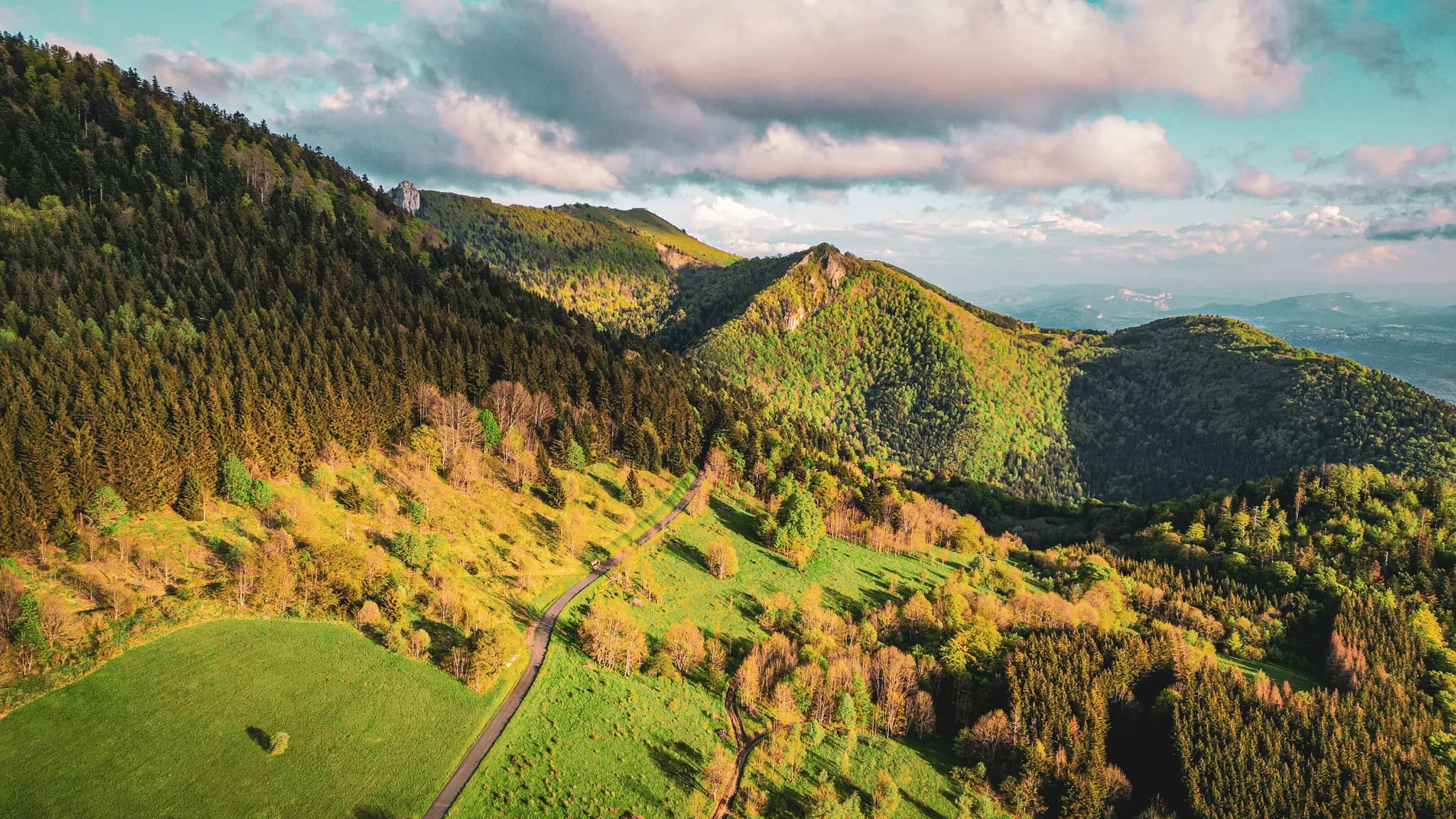Het weelderige groene landschap van de Jura, valleien en bergen onder een heldere hemel, een uitnodiging tot avontuur.