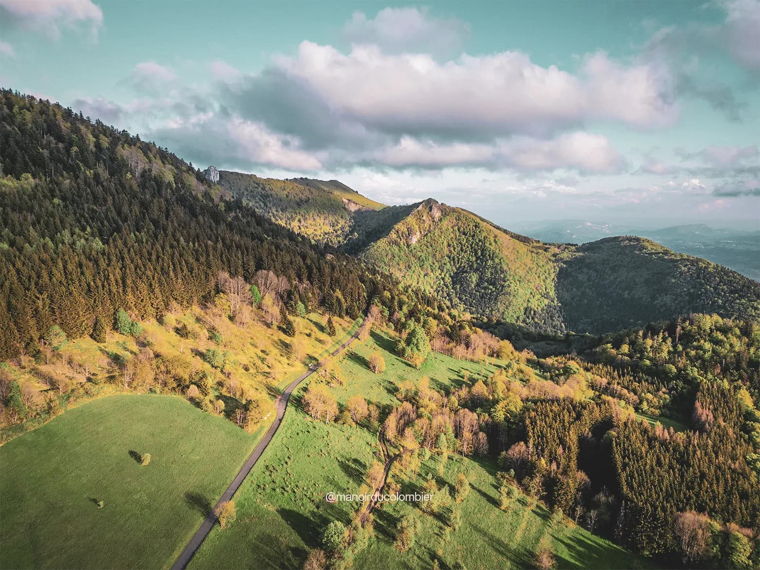 Paysage verdoyant du Grand Colombier, avec sentiers sinueux et sommets majestueux. Un appel à l'aventure !