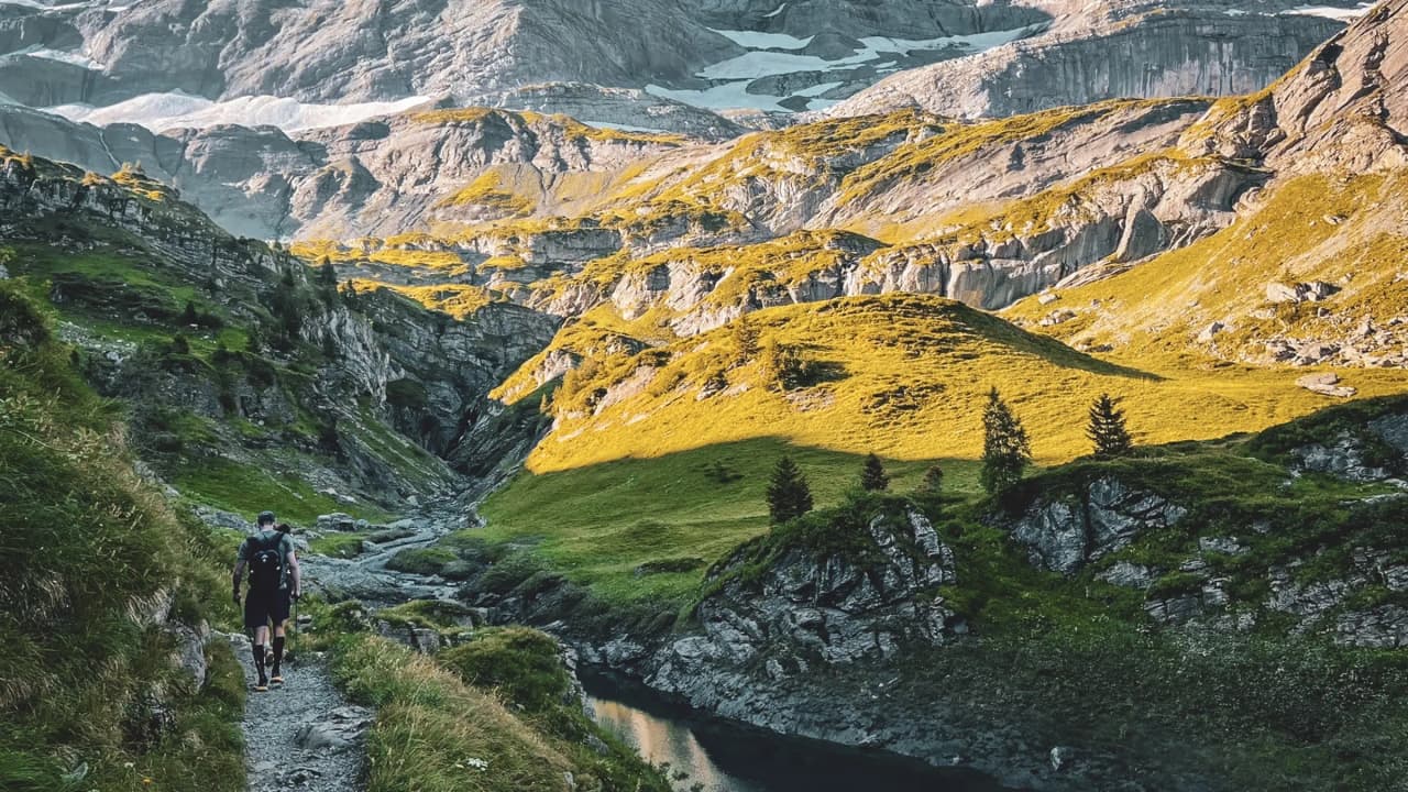 A hiker on an alpine trail, surrounded by mountainous landscapes and glistening lakes.