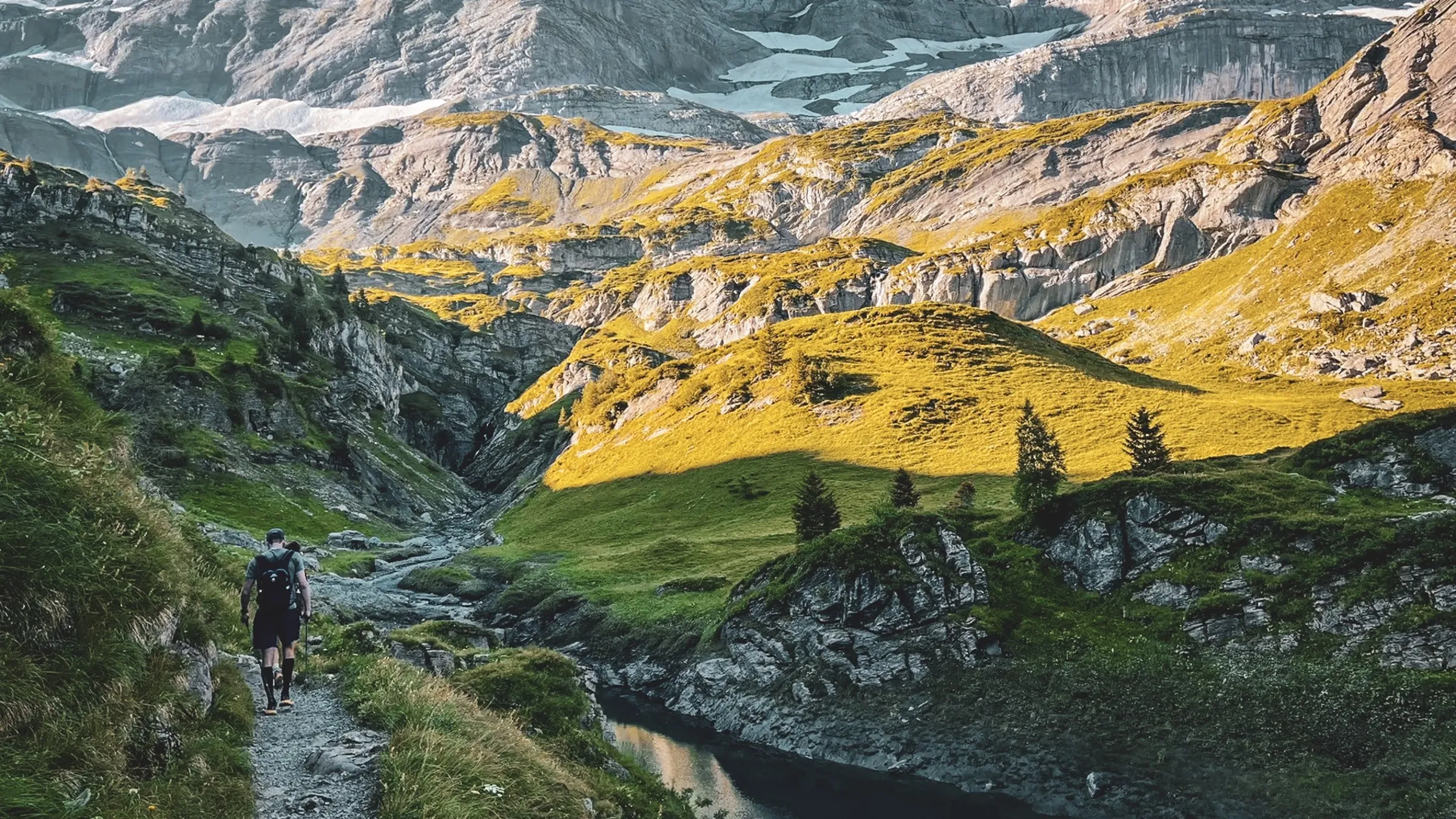 Un randonneur sur un sentier alpin, entouré de paysages montagneux et de lacs scintillants.