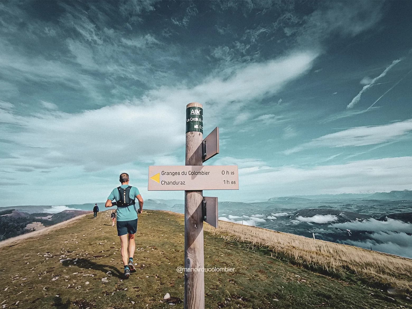 Un coureur sur un sentier montagneux avec une vue panoramique sur le Jura et le lac du Bourget.