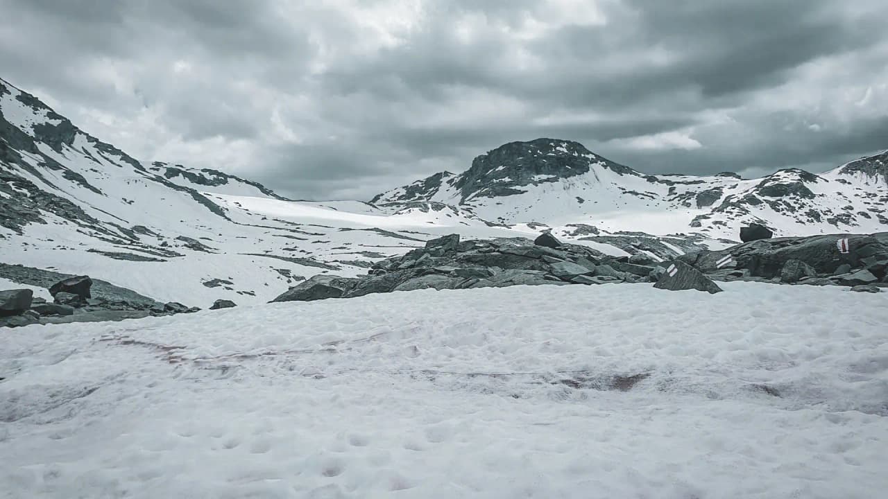 A majestic Alpine landscape, snowy and mountainous, under cloudy skies, perfect for adventure.