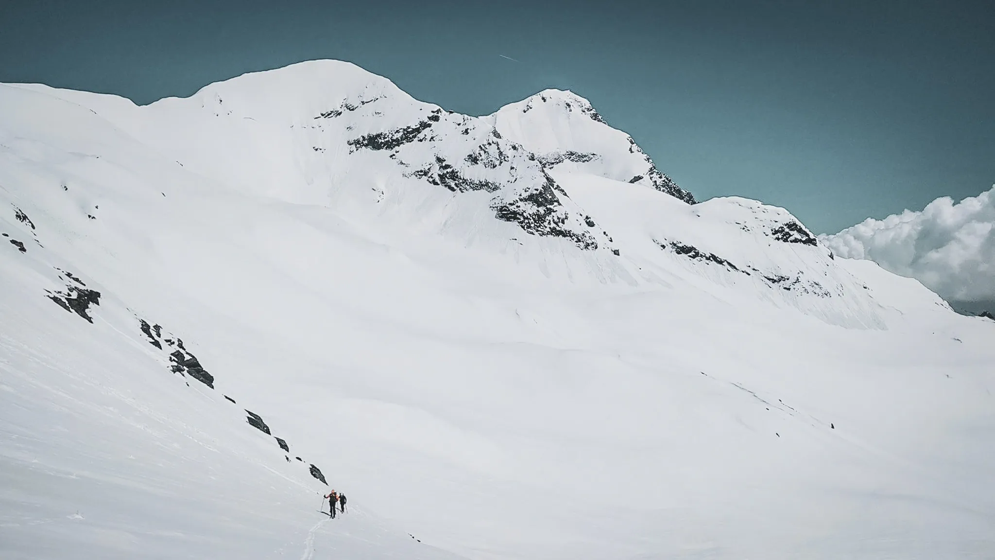 Two hikers on the immaculate glaciers of the Vanoise, under a soothing blue sky.