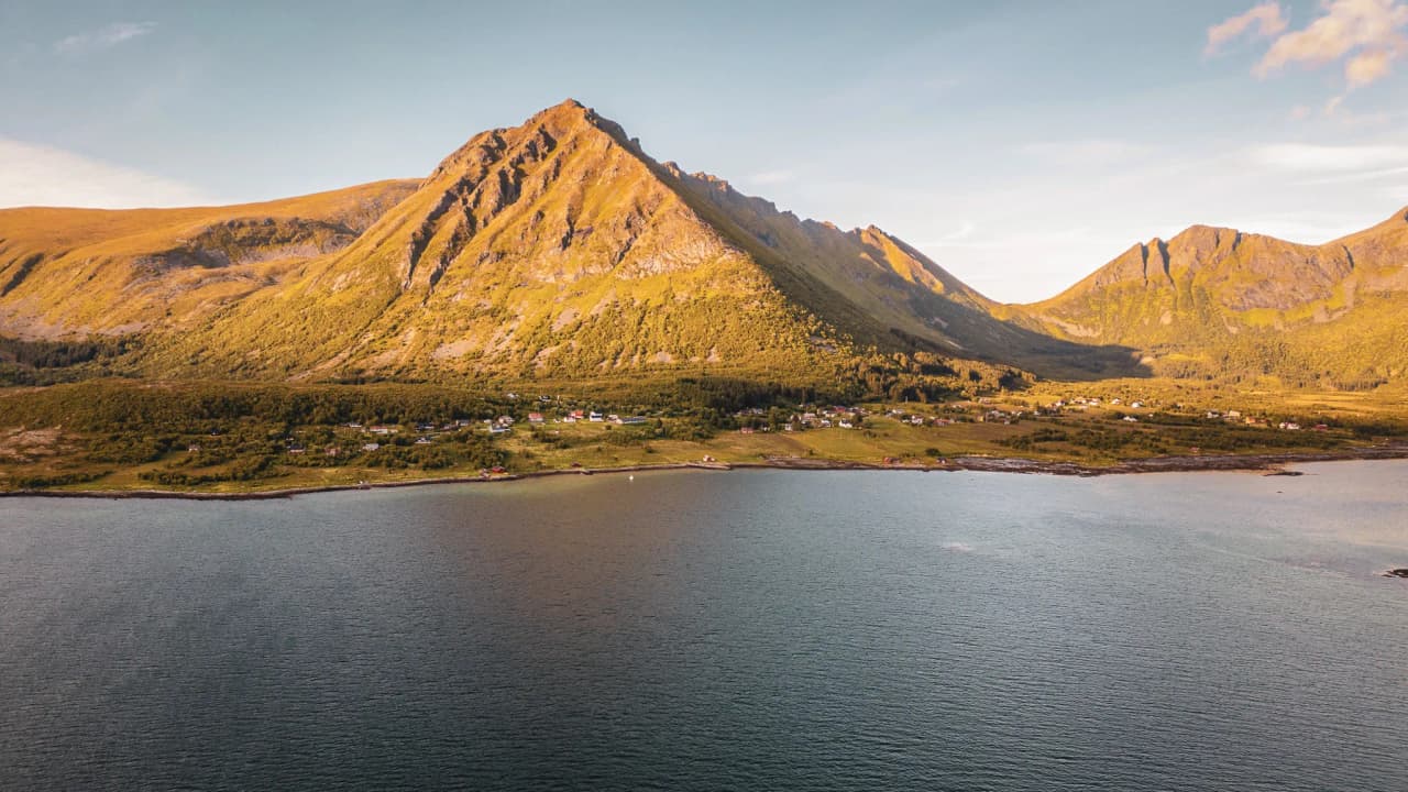 Golden mountains overlooking picturesque waterside dwellings in the Lofoten Islands.