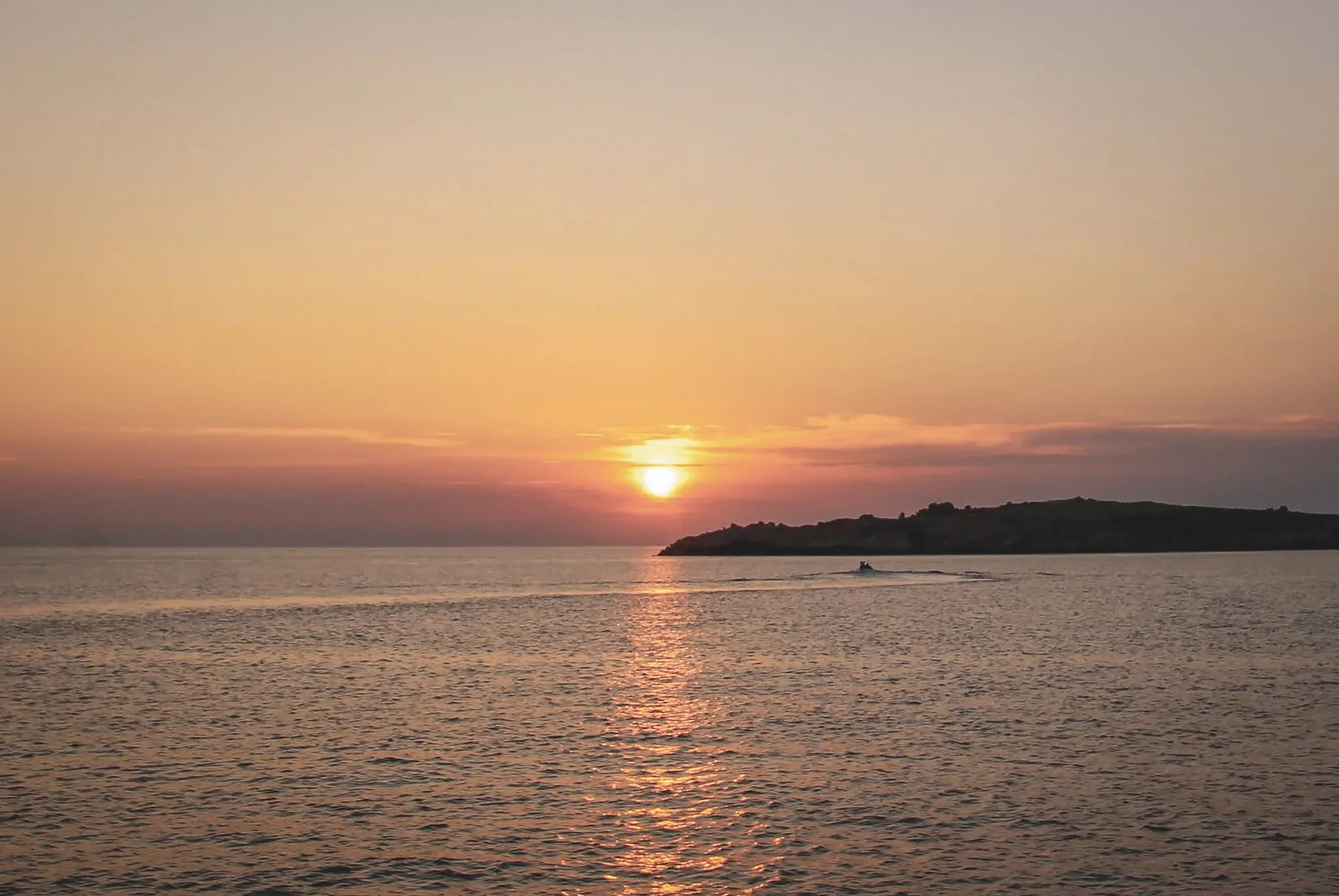 Coucher de soleil sur la mer, silhouette d'une île, invitation à la découverte en Corse.