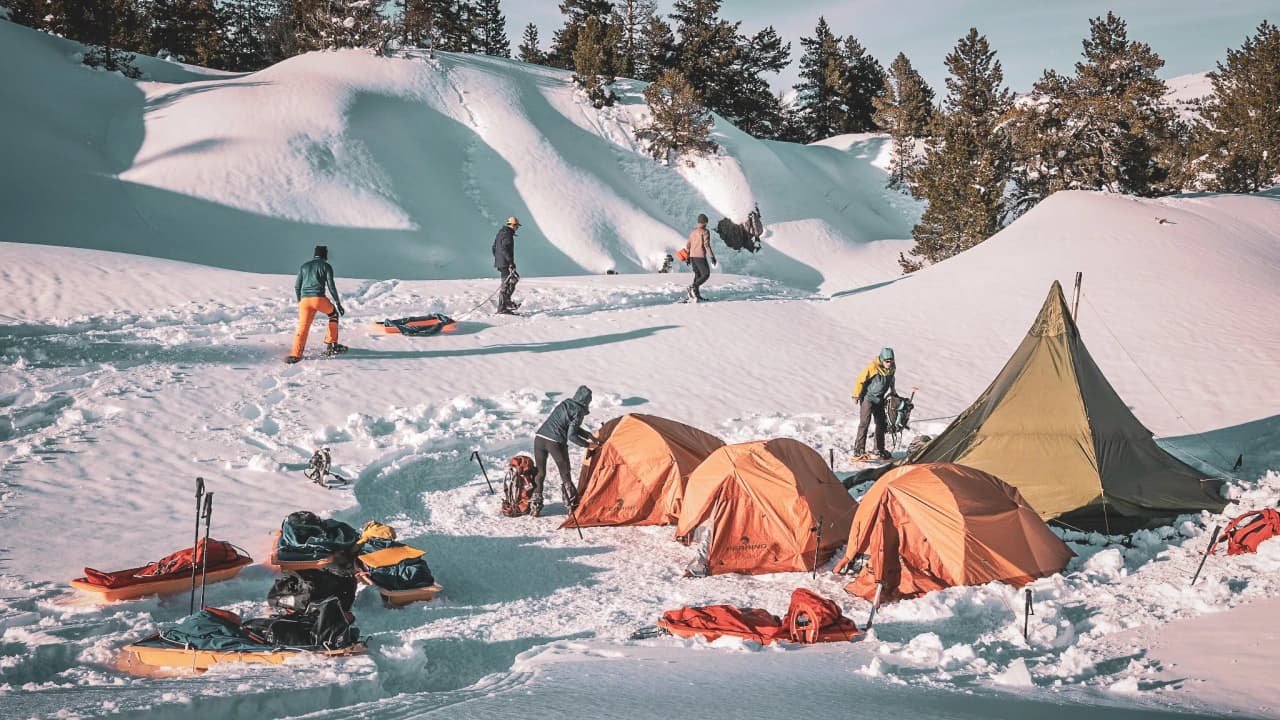 Een team dat druk bezig is met de voorbereidingen voor een bivak in een tipi, omringd door schitterende sneeuw in de Vercors.