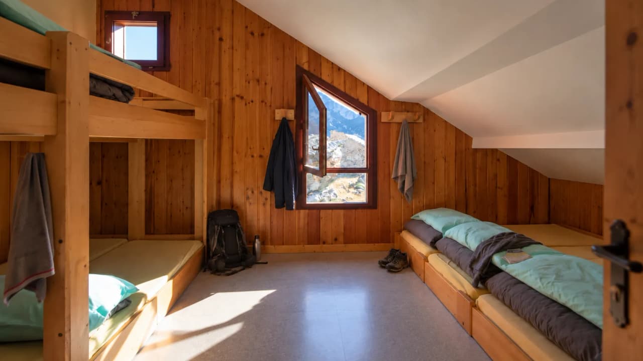 A room in a mountain hut, with comfortable beds and a panoramic view of the countryside. Perfect for a trek.