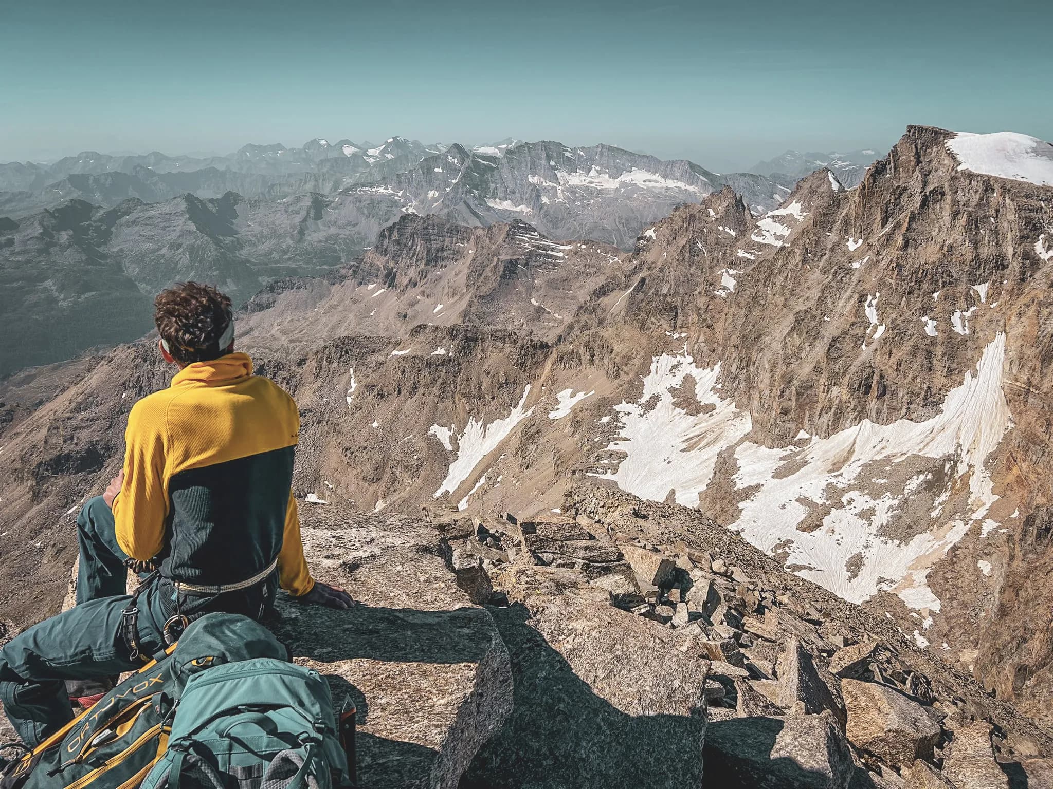 Mountaineer contemplating a majestic mountain panorama at the summit of Gran Paradiso.