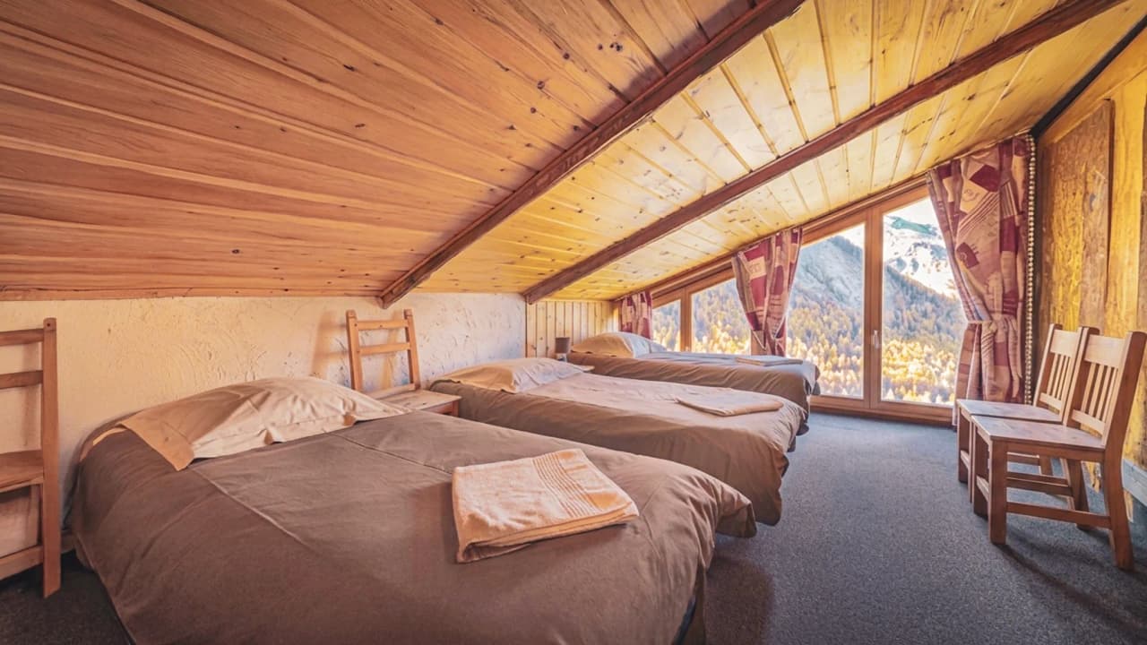 Chambres confortables sous un plafond en bois, vues panoramiques sur les montagnes environnantes.