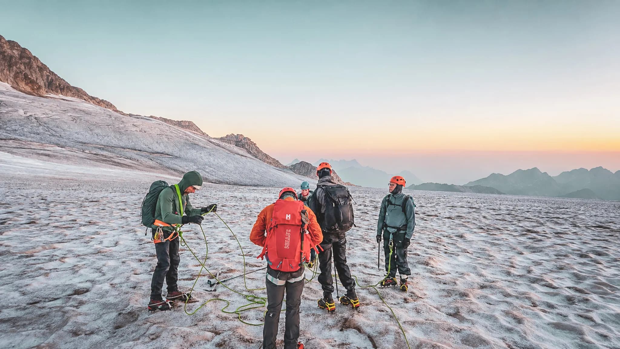 Groupe d'alpinistes sur un glacier au lever du soleil, prêts pour une aventure estivale à Chamonix.