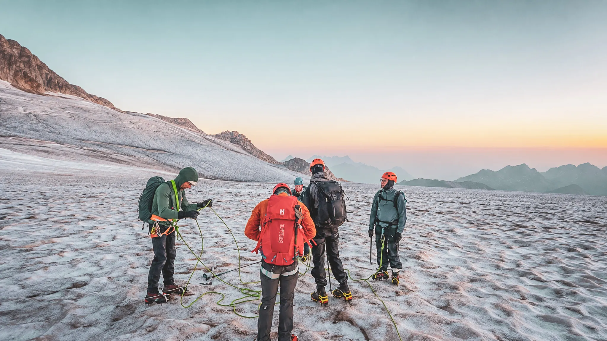 Groupe d'alpinistes sur un glacier au lever du soleil, prêts pour une aventure estivale à Chamonix.