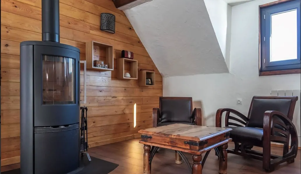 Un coin chaleureux avec poêle, fauteuils en bois et stylés dans une cabane cosy au Vercors.