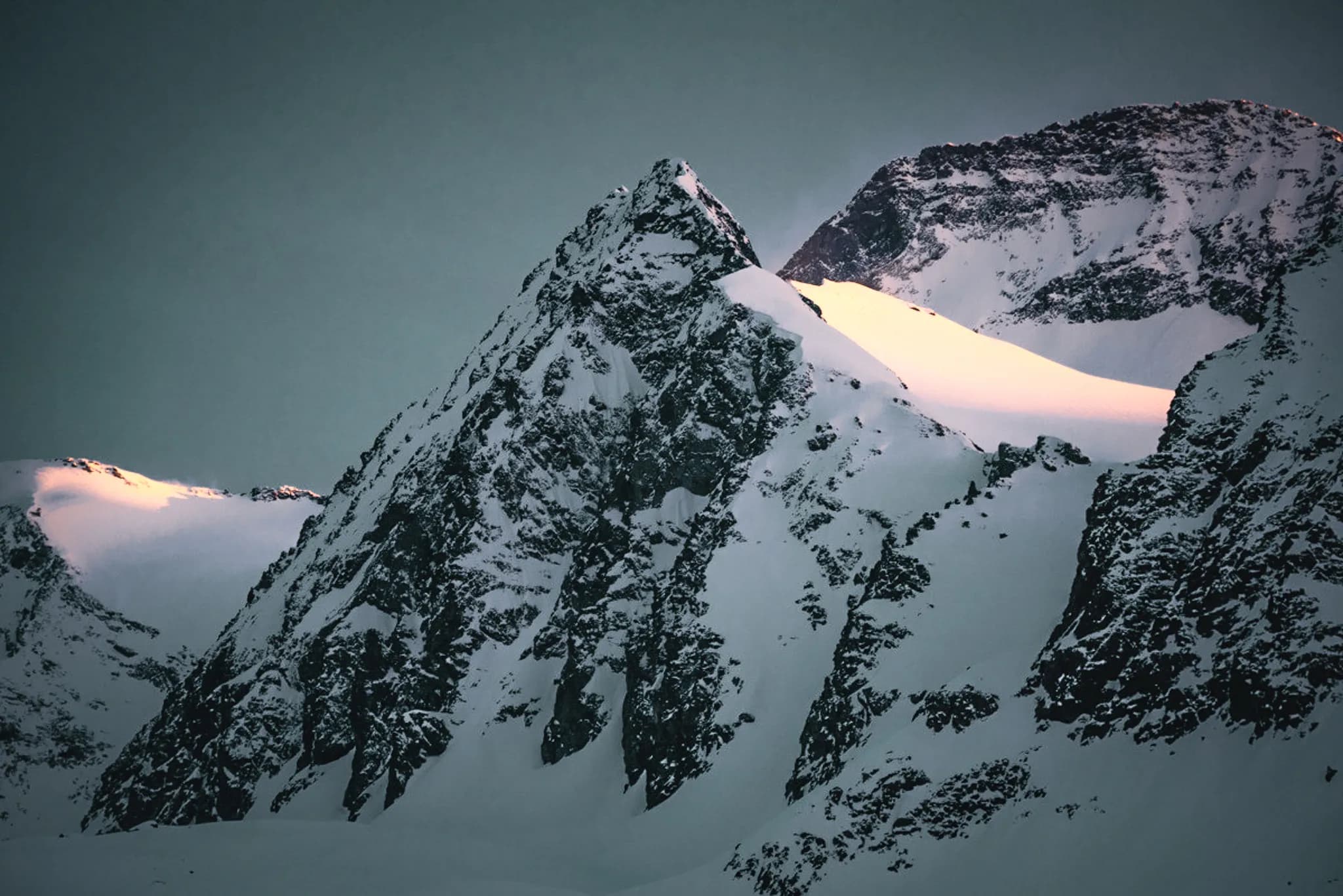A majestic mountain peak shrouded in snow, bathed in golden morning light.