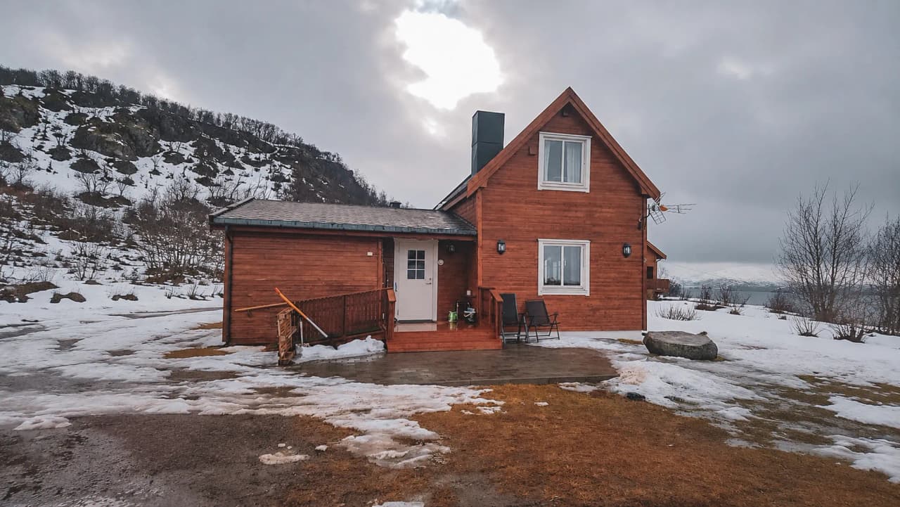 Chalet en bois dans un paysage enneigé de Laponie, idéal pour une aventure en traîneau à chiens.