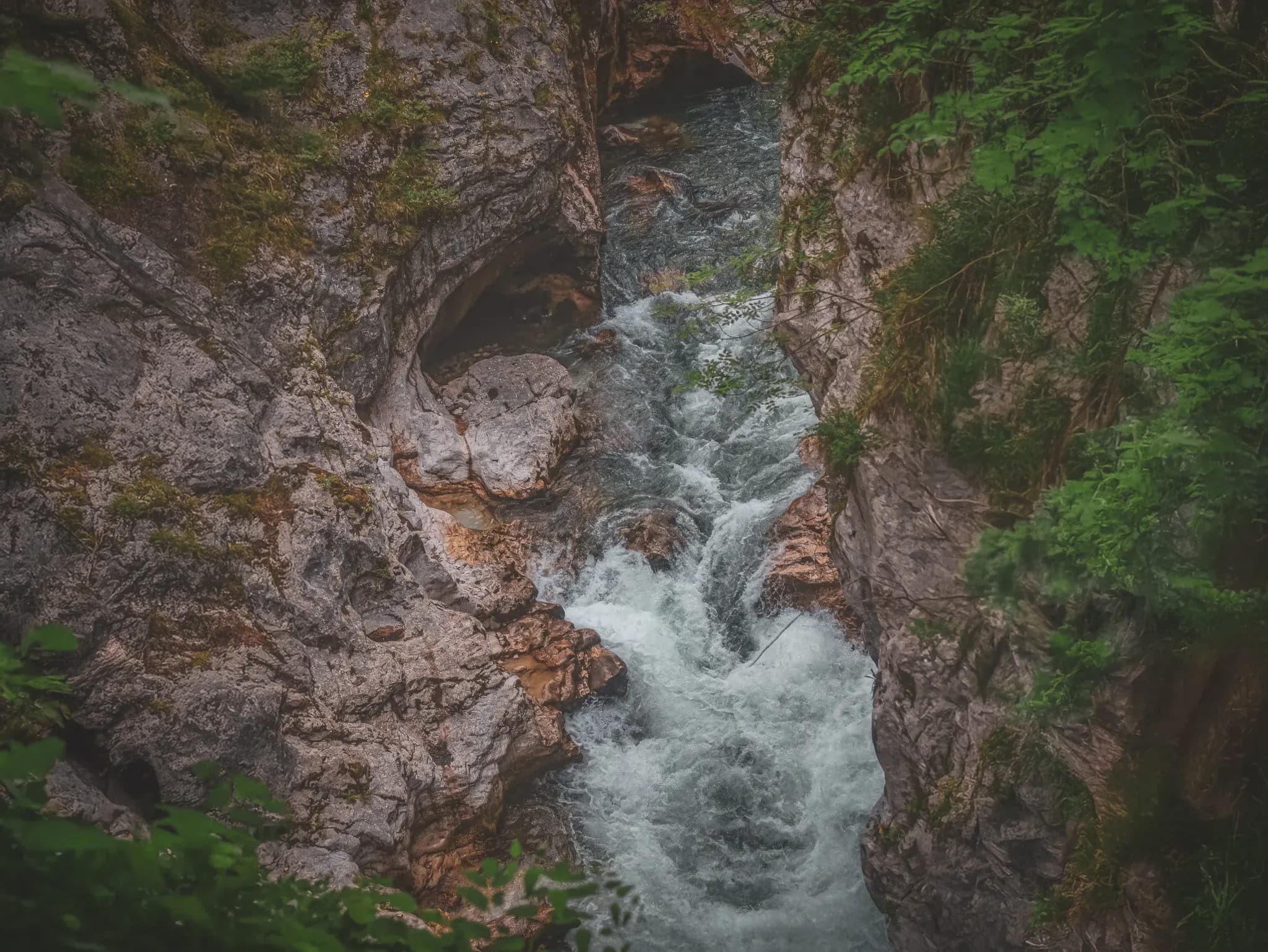 A tumultuous torrent flows between lush green rocky cliffs, a promise of adventure.
