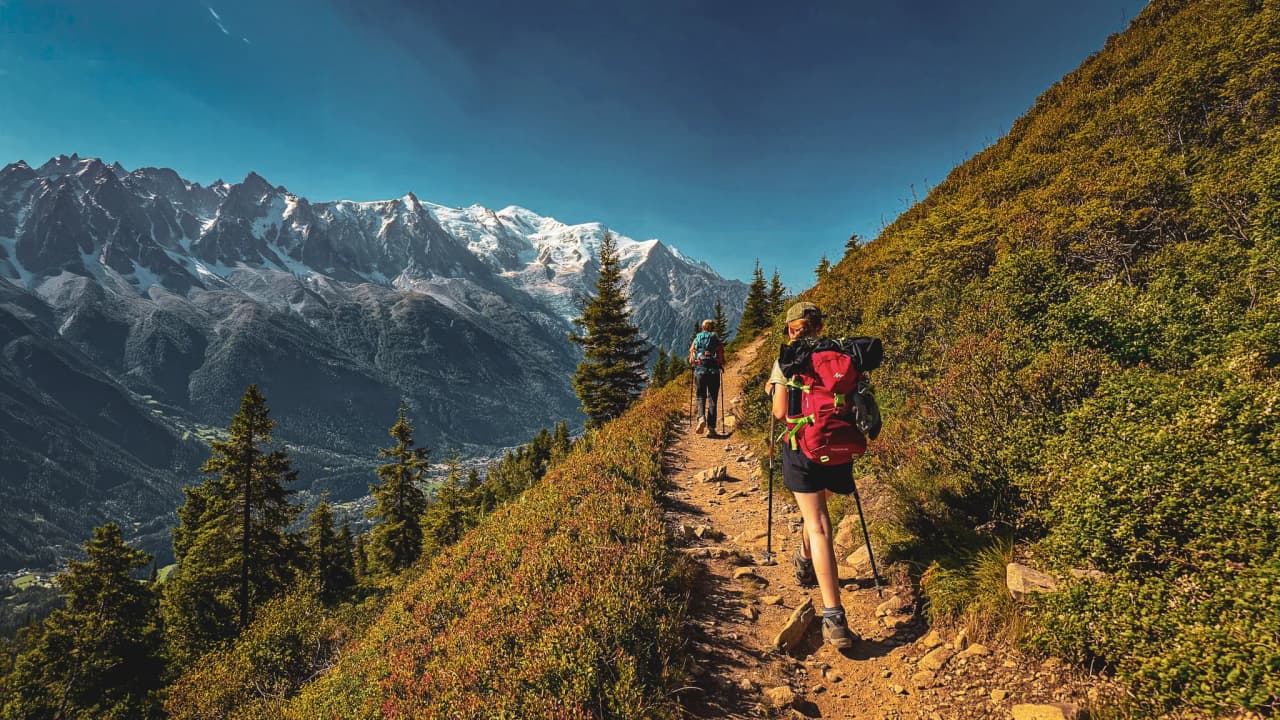 Hikers on a picturesque trail with panoramic views of the majestic Mont Blanc mountains.