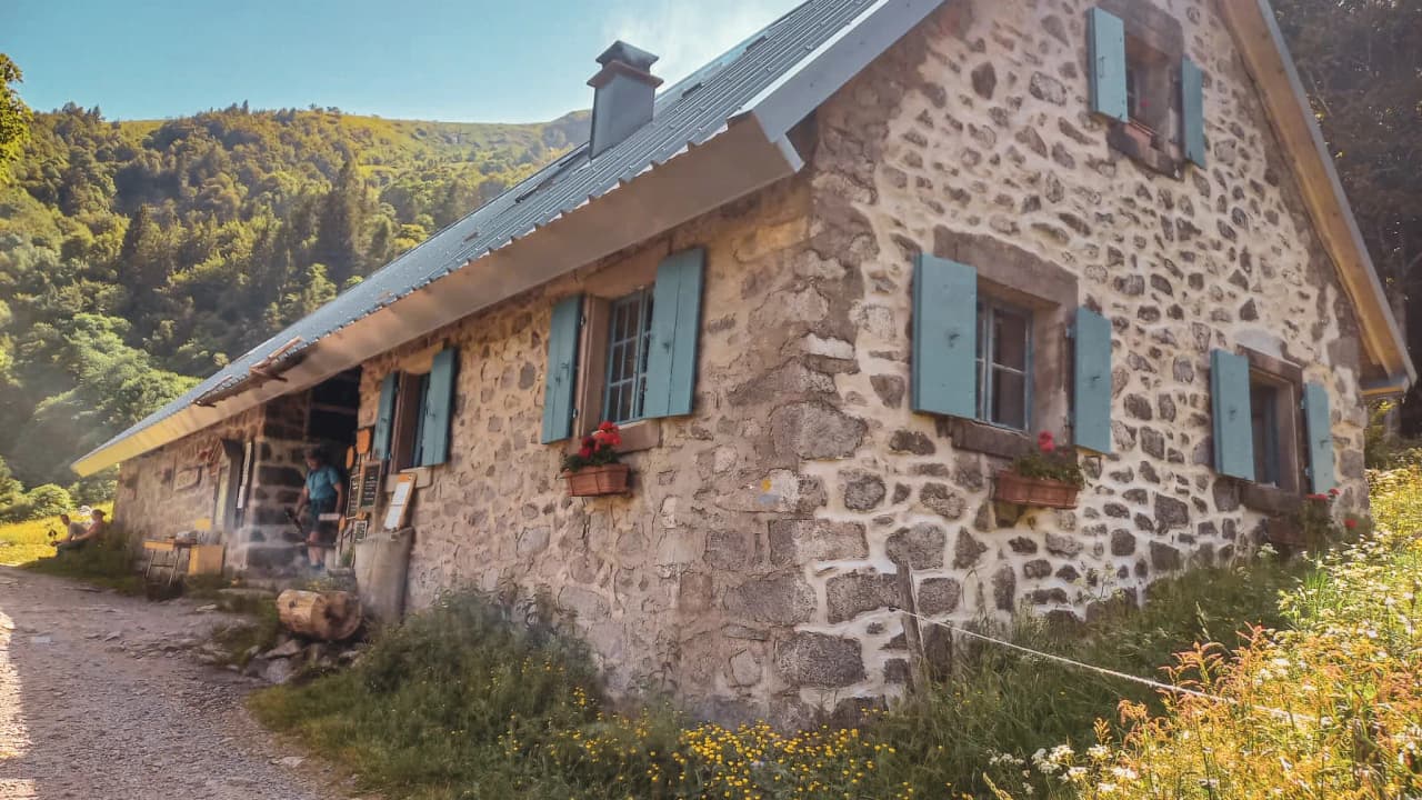 Refuge pittoresque en pierre, entouré de verdure luxuriante dans les Vosges, invitant à l'aventure.