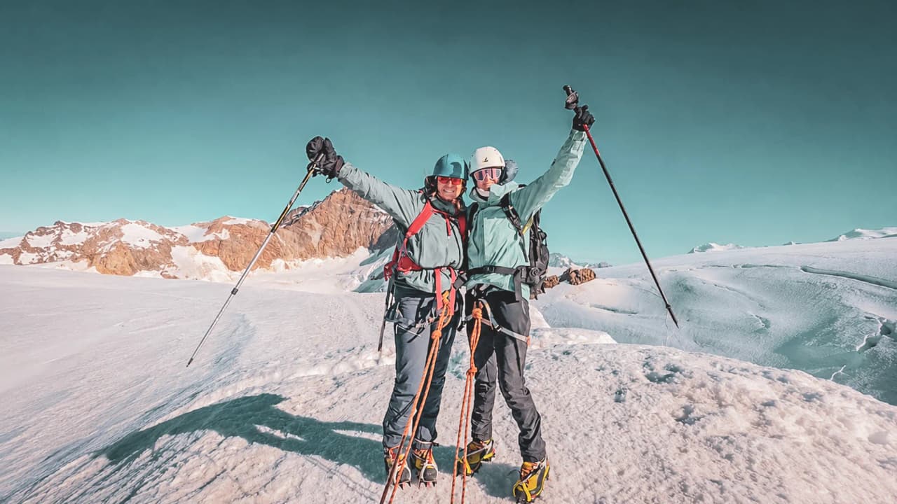 Two smiling mountaineers out in the mountains, ready to conquer the snow-capped peaks.