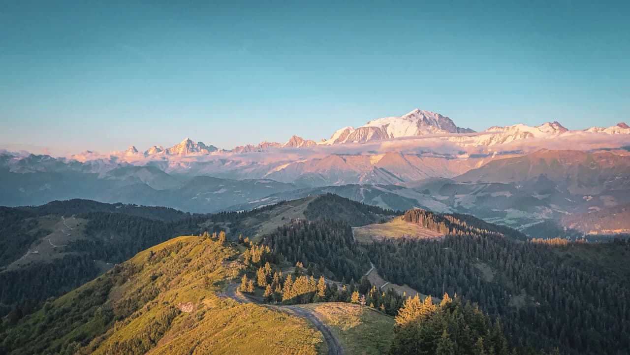 Panoramic view of the Alps, with the majestic Mont Blanc in the distance, lit up by the sun.