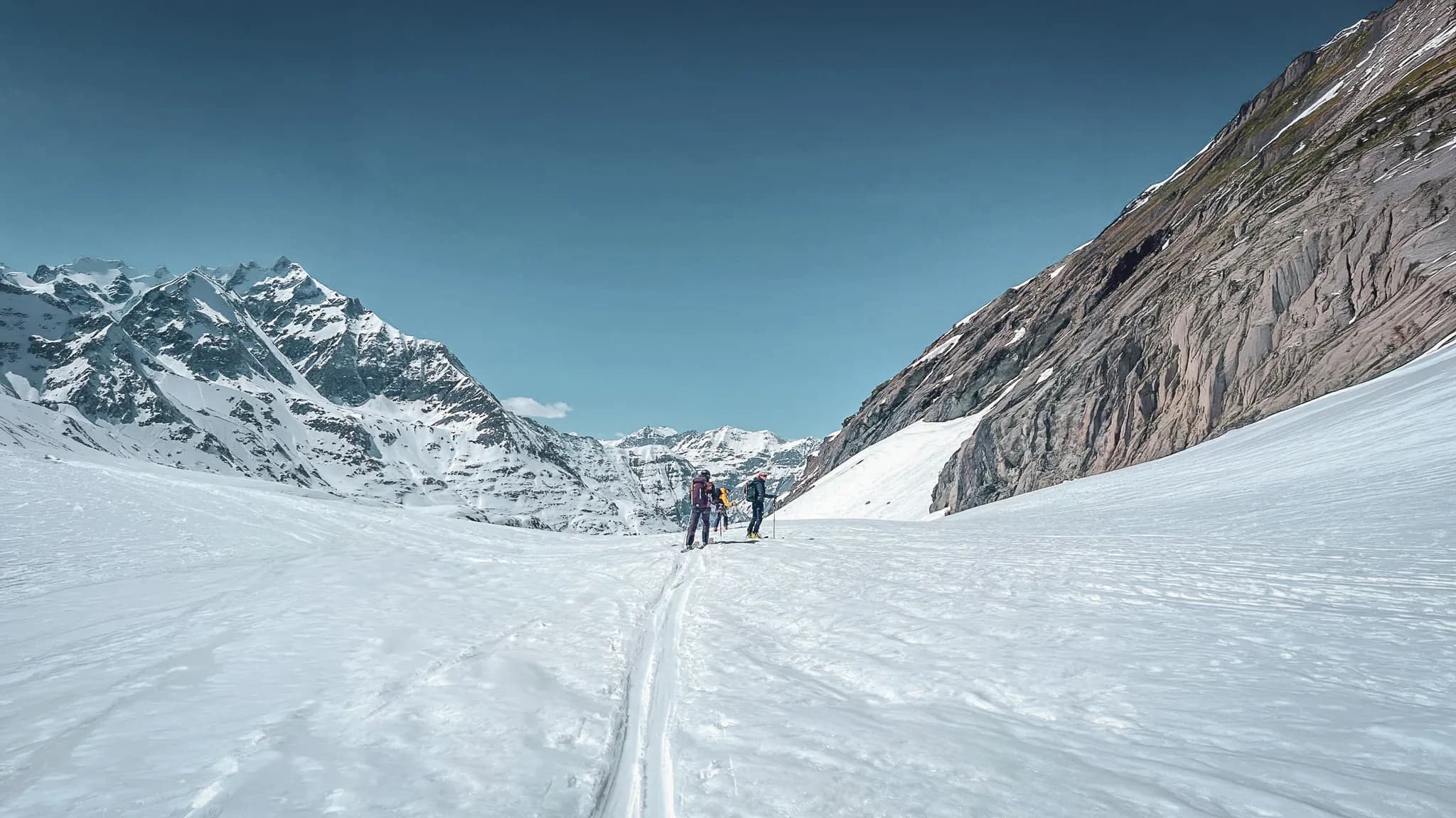 Groupe de skieurs sur un glacier, avec des montagnes majestueuses en arrière-plan. Aventure en pleine nature.