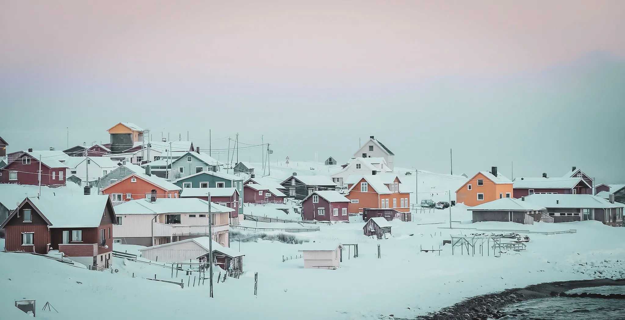 Charming, colourful chalets in Norwegian Lapland, surrounded by immaculate snow and pastel skies.