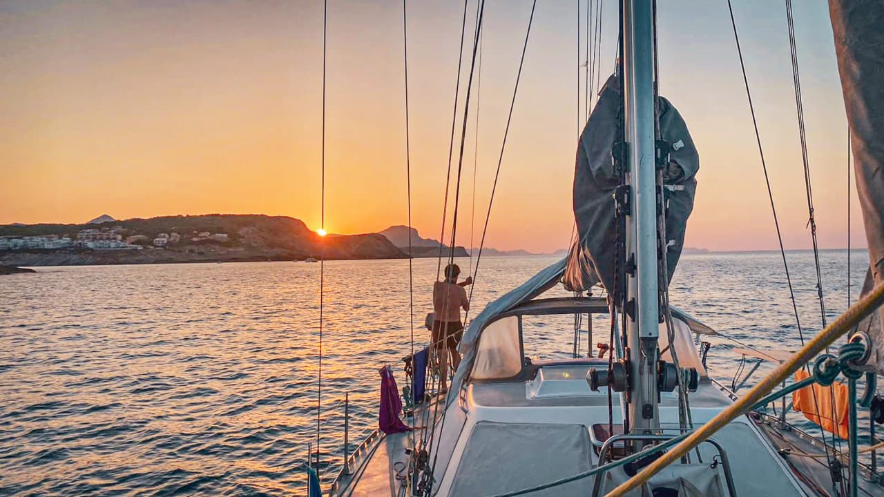 Sunset over the sea, a sail on a boat, the tranquillity of the Balearic Islands in the background.