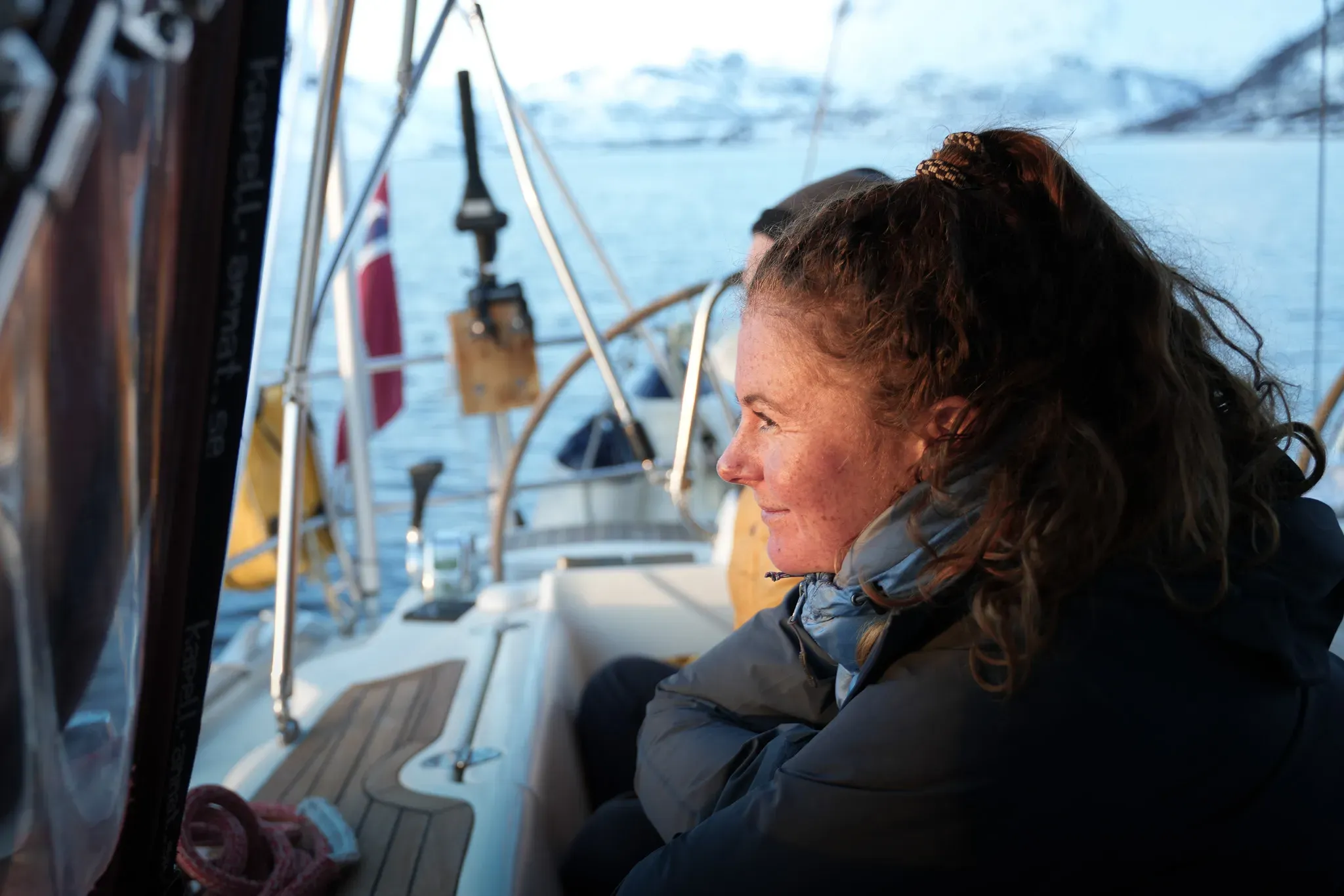 An adventurer contemplating the majestic landscapes of the Lyngen Alps from a sailing boat.