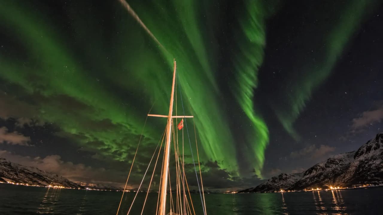 Voilier illuminé sous les aurores boréales dans les Lofoten, un spectacle magique du nord.