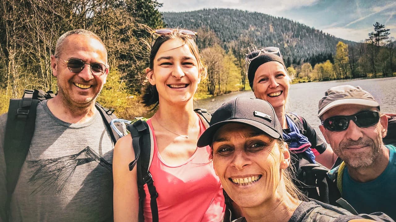 A smiling group by a lake, ready for a mountain adventure in the Vosges.
