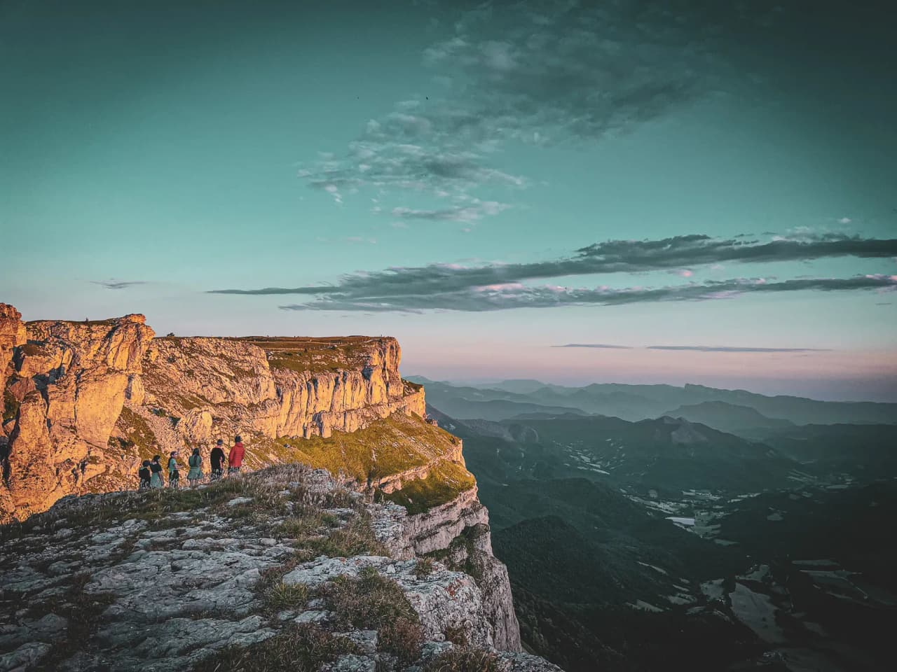 A group of explorers walking on a rocky plateau surrounded by majestic mountains in the Vercors.