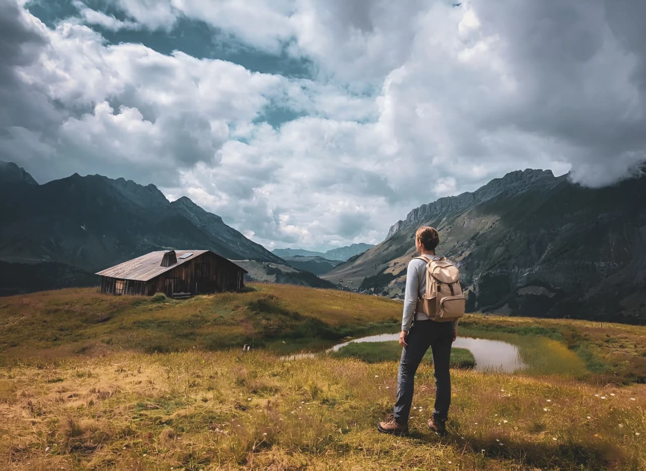 A hiker contemplating majestic Alpine scenery against a cloudy sky.