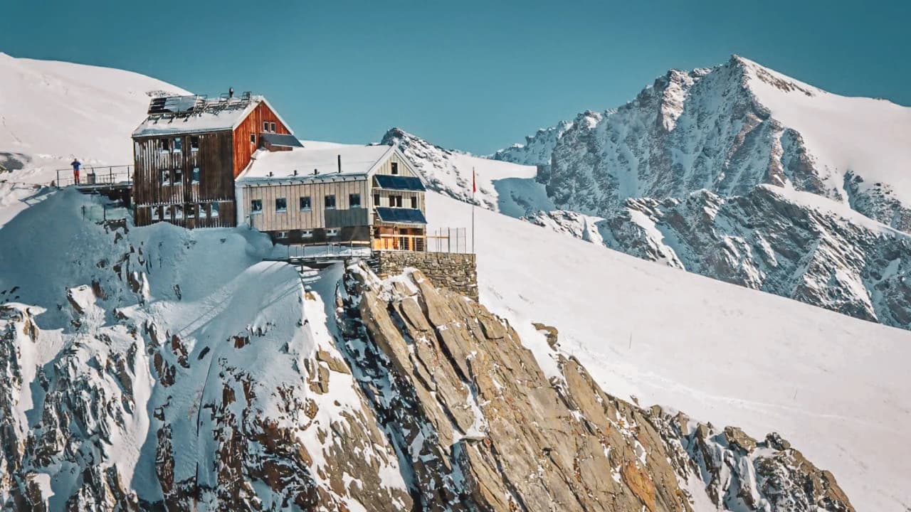 Refuge alpin perché sur une falaise enneigée, offrant des panoramas époustouflants sur les montagnes.