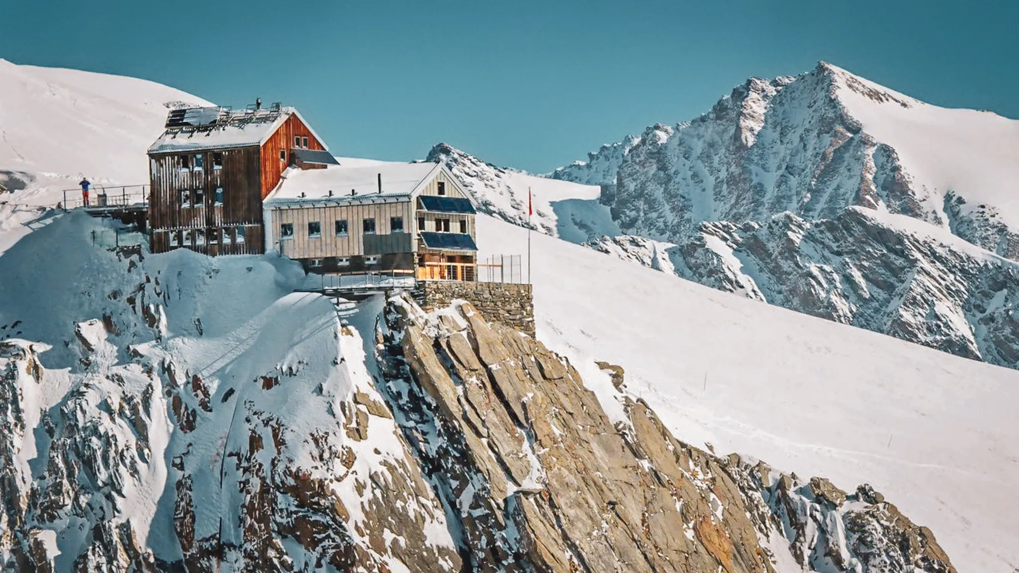 Refuge alpin perché sur une falaise enneigée, offrant des panoramas époustouflants sur les montagnes.