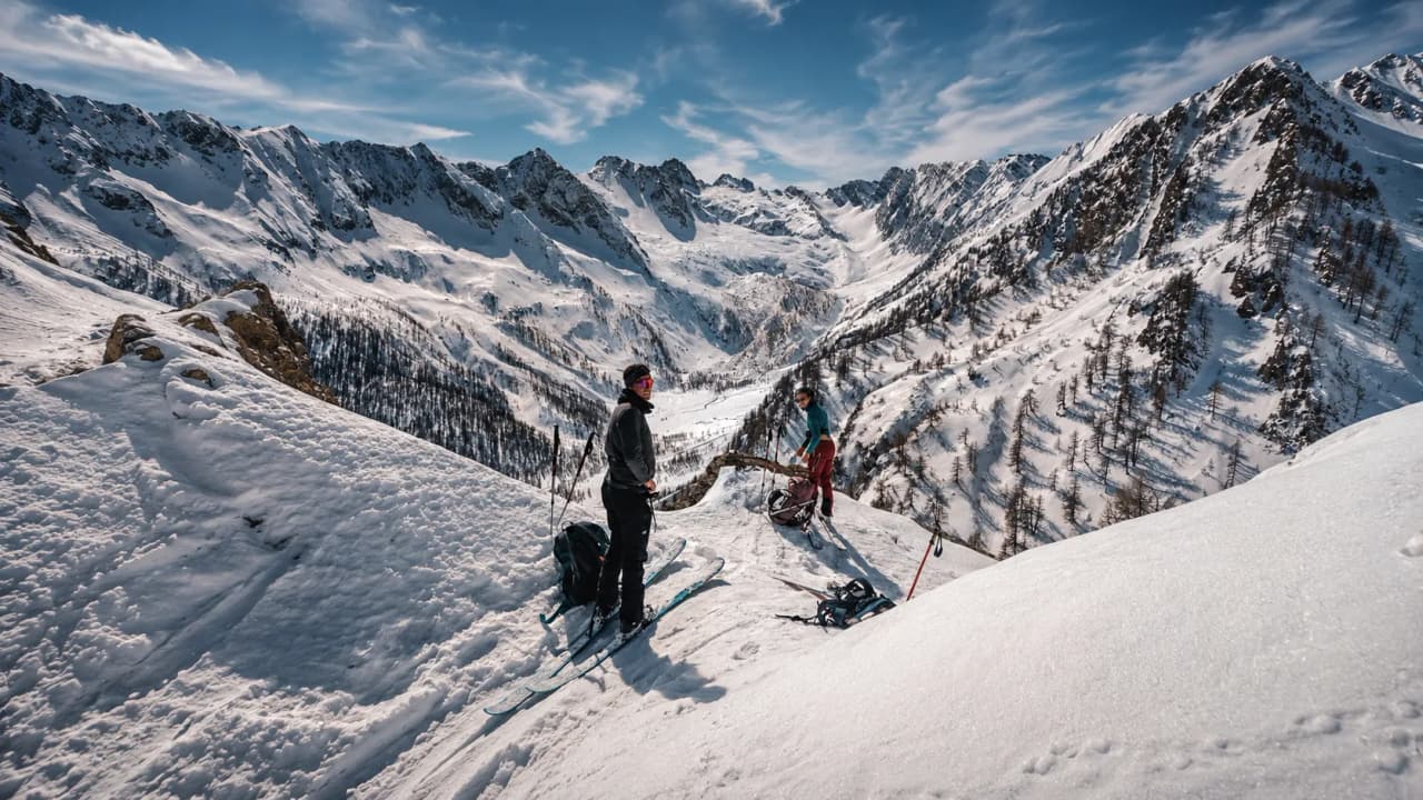 Deux skieurs au sommet d'une montagne enneigée, admirant un panorama époustouflant.