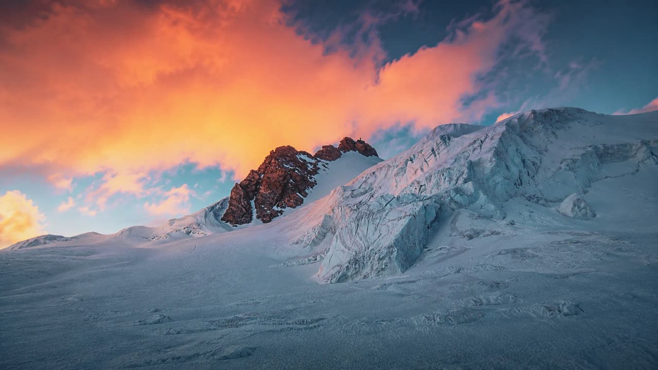 Een schitterende zonsondergang boven besneeuwde bergtoppen en gletsjers, een belofte van avonturen in de Alpen.