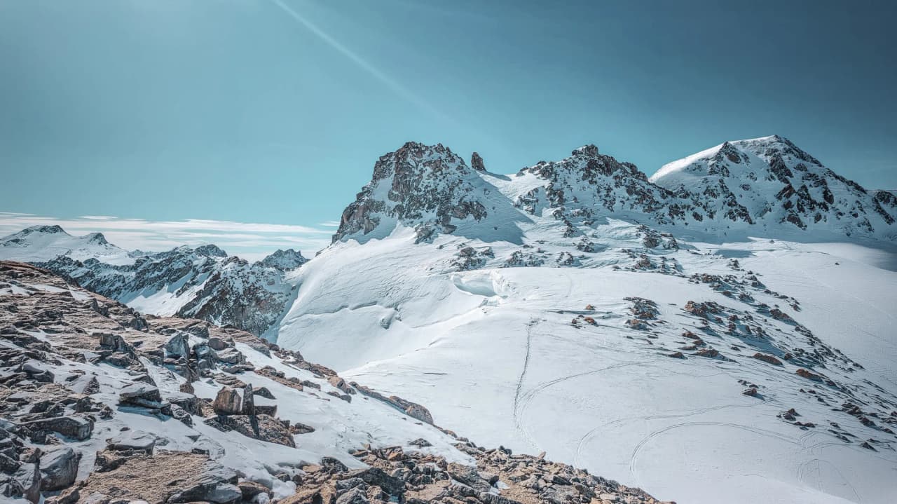 A panel of majestic mountains and glistening glaciers under a brilliant blue sky.