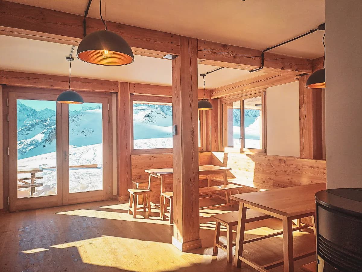 Warm, light-filled wooden interior with views of the snow-capped mountains.