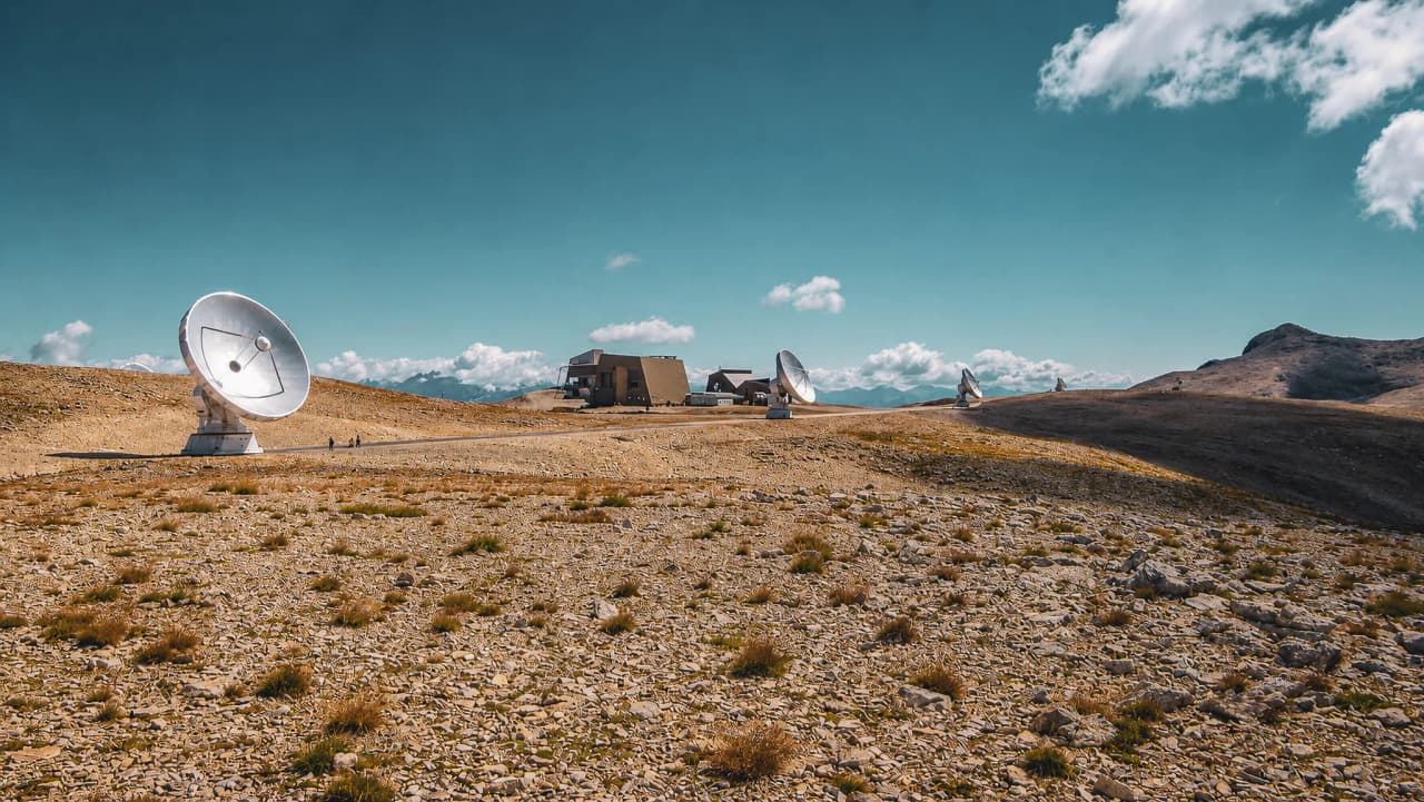 Een uitgestrekte rotsvlakte met telescopen, onder een levendige, zonnige hemel, nodigt uit tot avontuur.