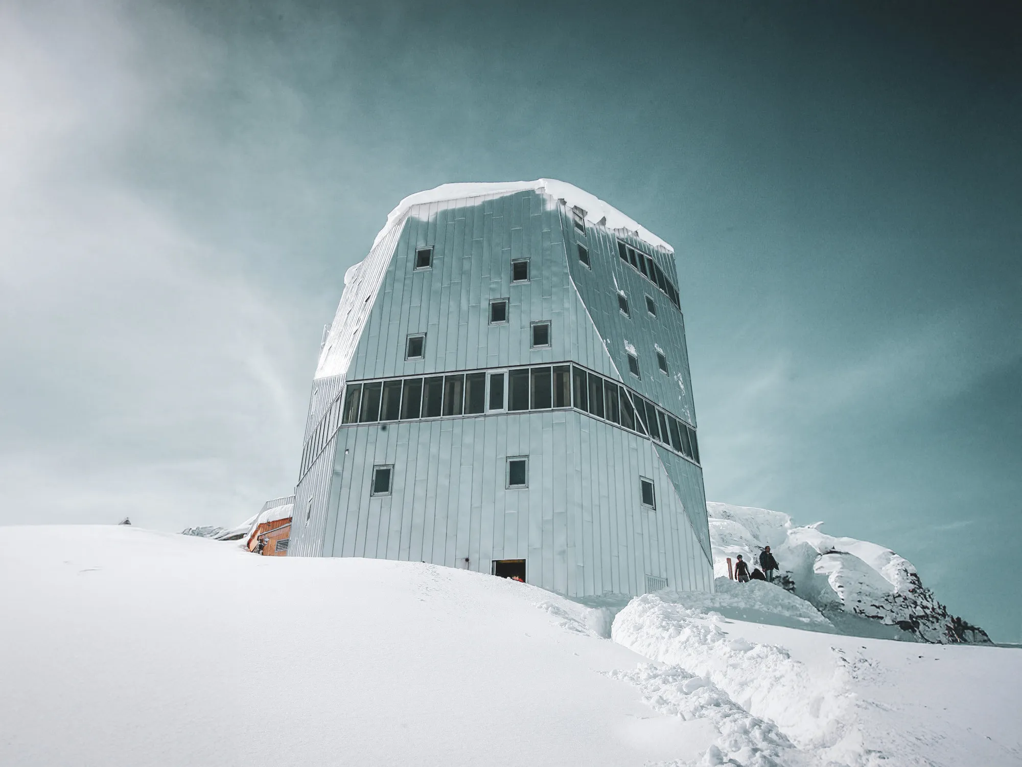 Refuge moderne sur neige éblouissante, entouré de sommets majestueux des Alpes.