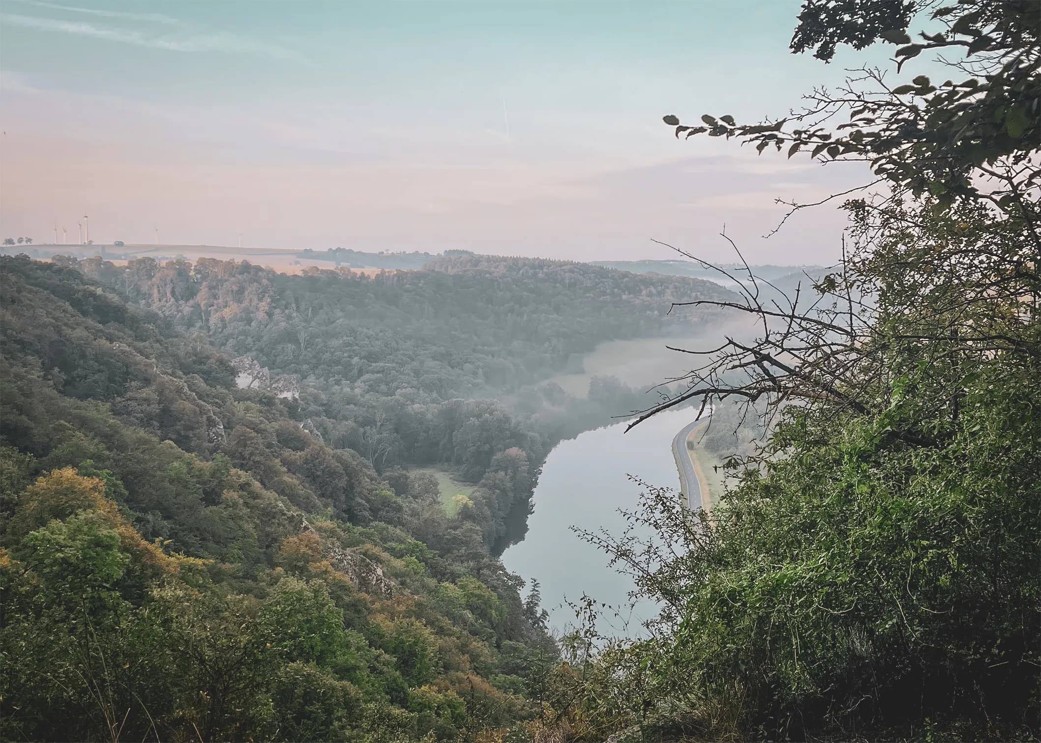 Vue panoramique d'une vallée verdoyante avec une rivière sinueuse, idéale pour l'aventure.
