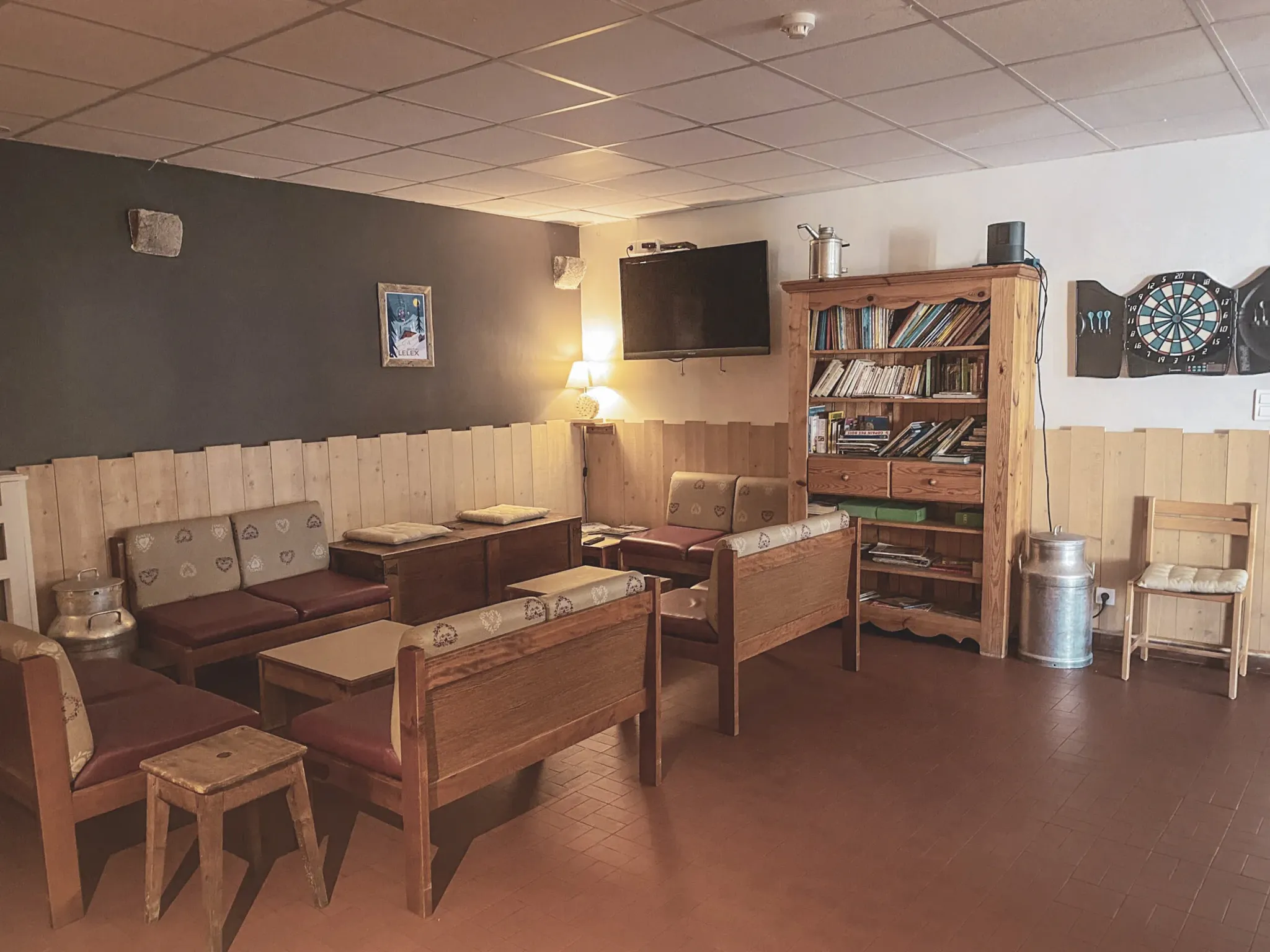 Een gezellige lounge met houten bank, boekenkast en warme sfeer, ideaal om te ontspannen na een avontuur.