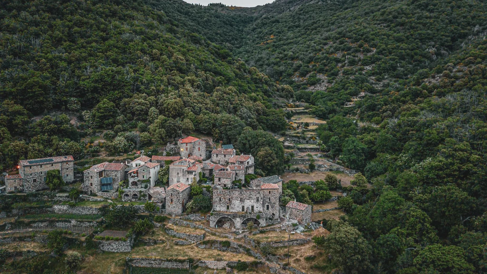A picturesque village nestling in the Cévennes, surrounded by lush greenery and terraces.