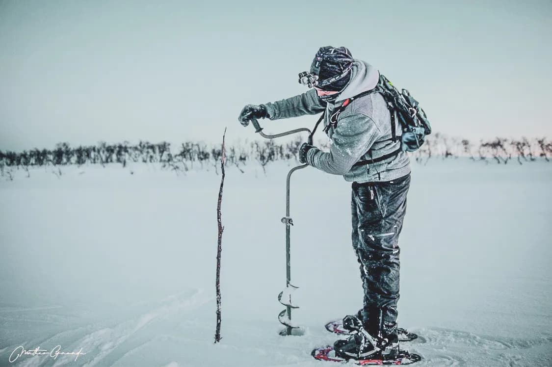 An adventurer on snowshoes breaks through the ice, exploring the vast snow-covered landscapes of Finnmark.