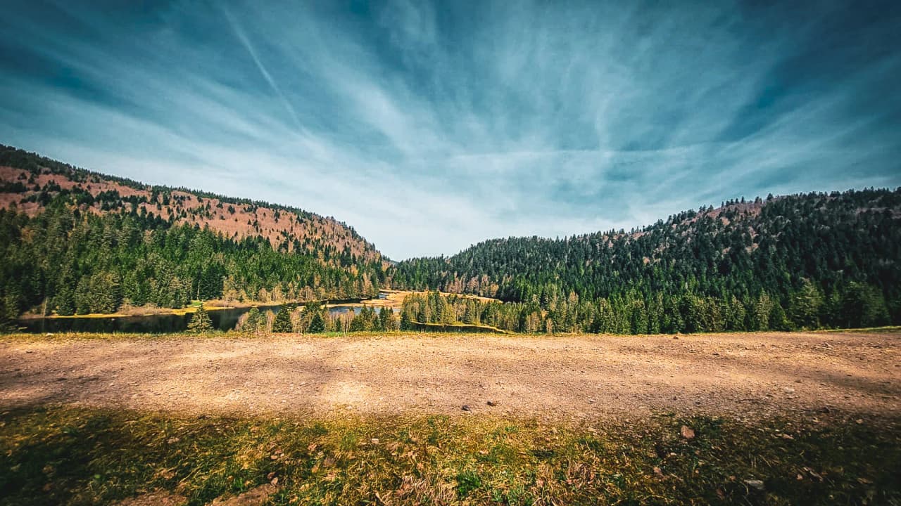 A Vosges landscape of lakes and lush green forests under a blue sky, inviting you to escape.
