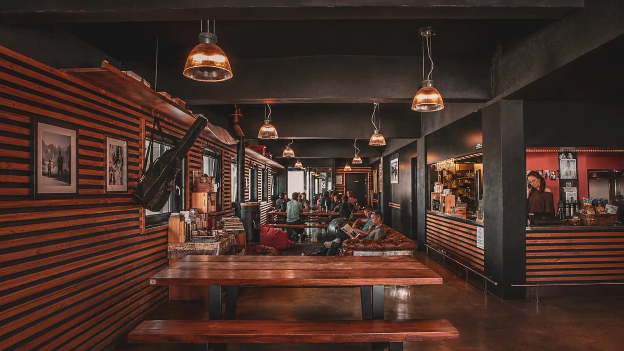 A cosy inn with wooden tables, hanging lights and relaxed travellers.