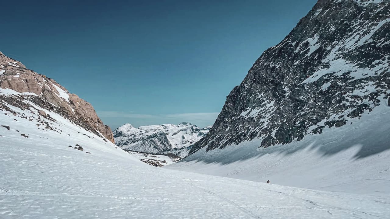 A vast glacial valley beneath a blue sky, guided by majestic mountains.