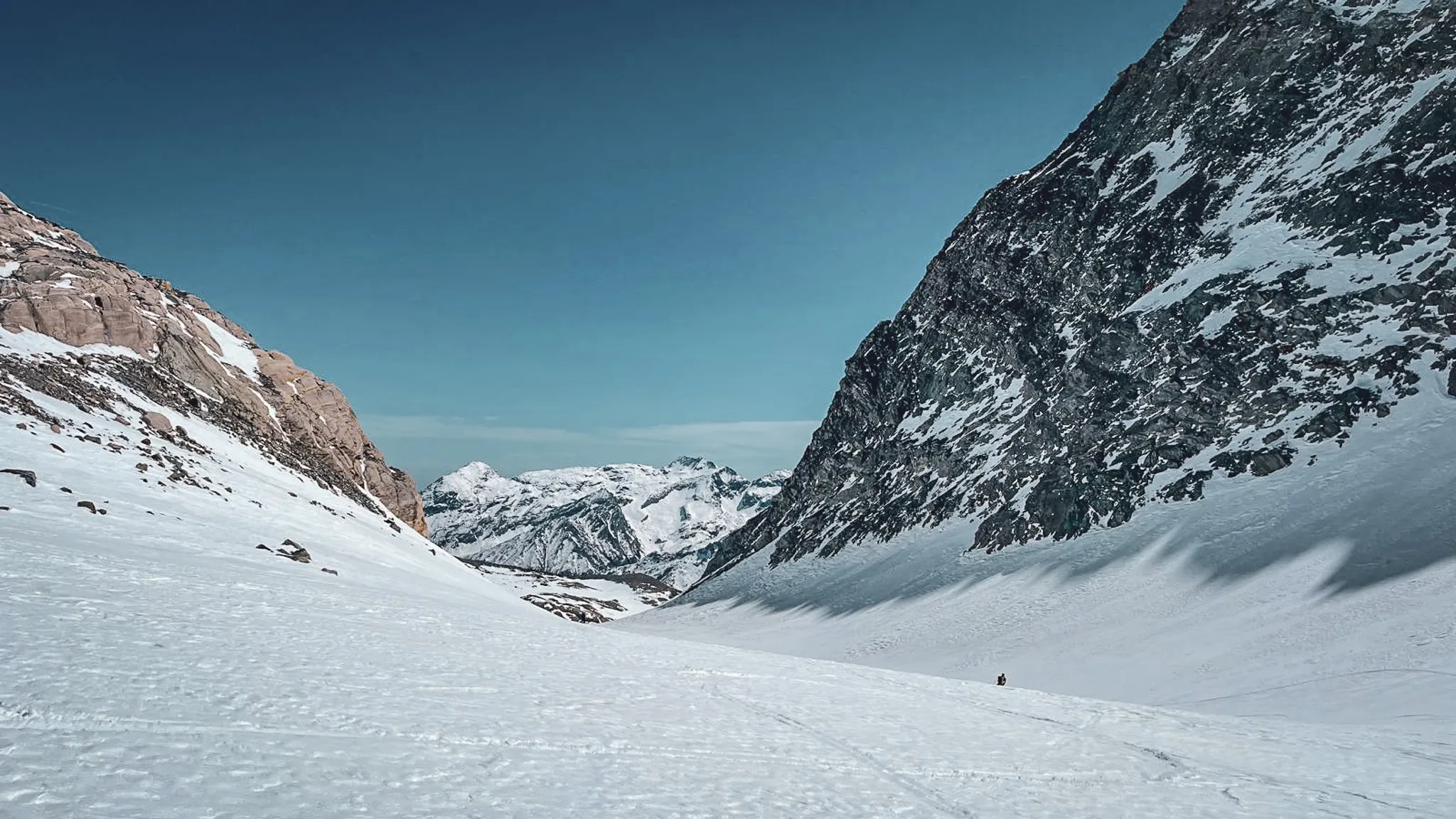 Vaste vallée glaciaire sous un ciel bleu, encadrée par des montagnes majestueuses.