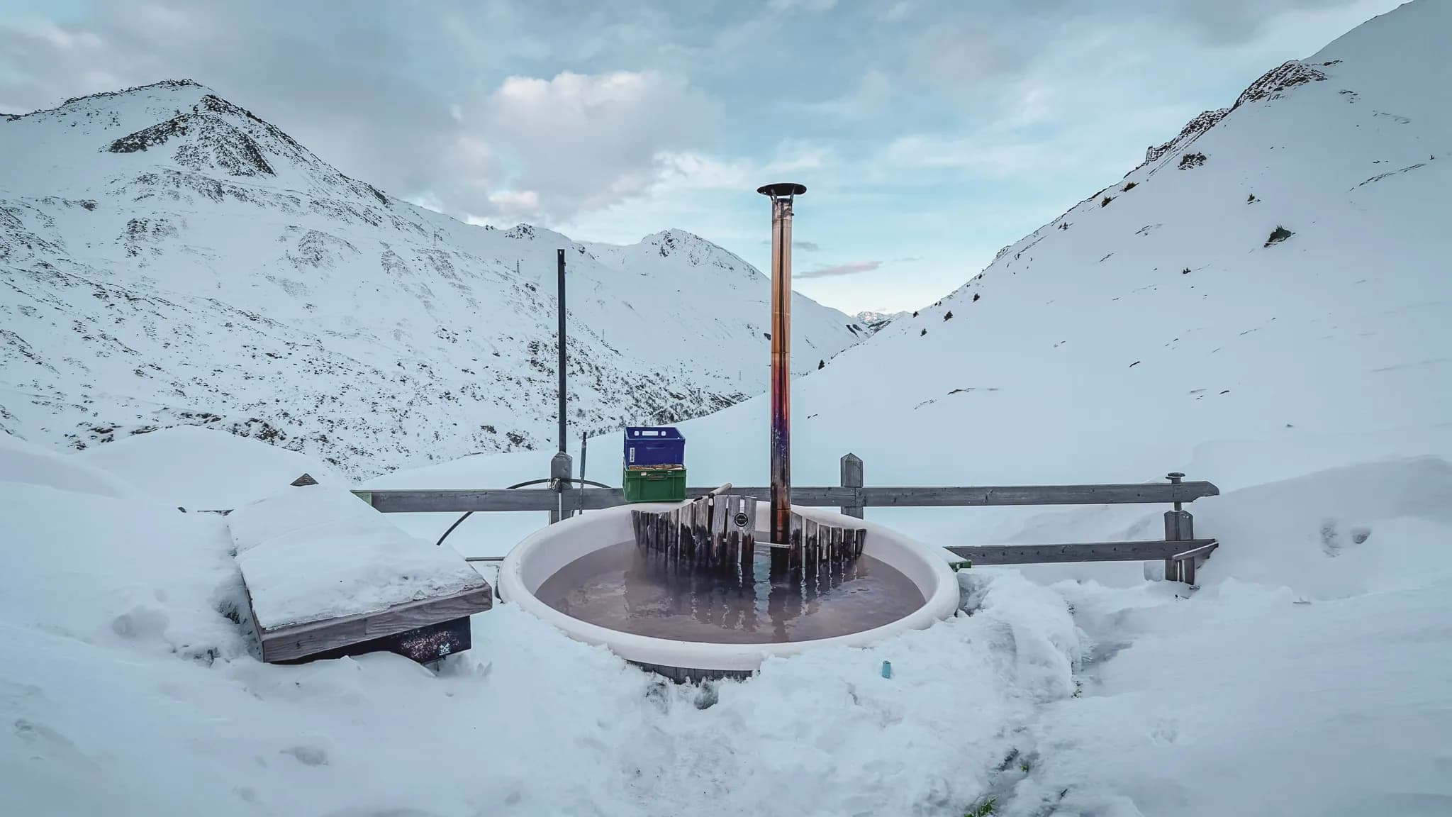 Accueillante baignoire chauffée entourée de montagnes enneigées, invitation à l'aventure alpine.
