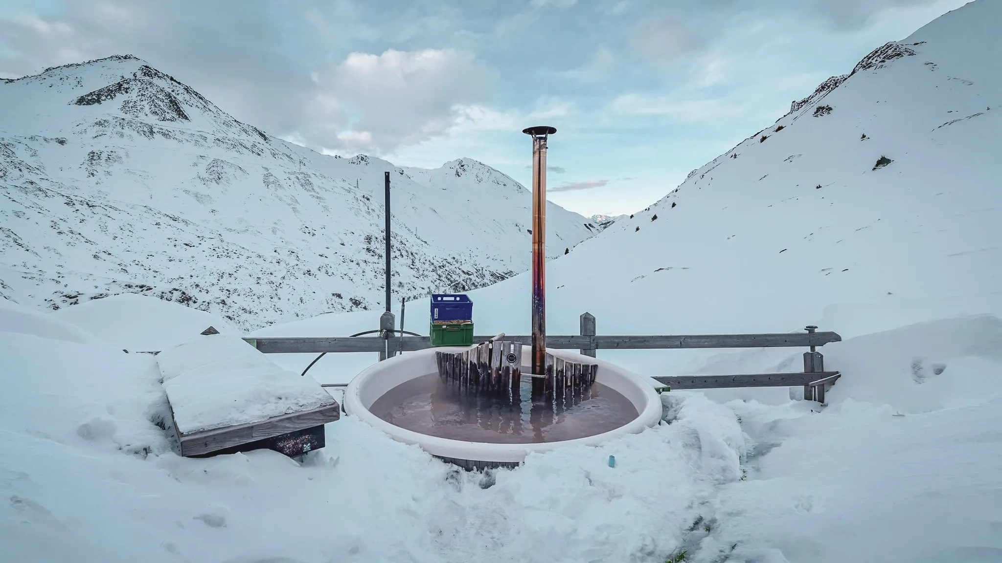 Accueillante baignoire chauffée entourée de montagnes enneigées, invitation à l'aventure alpine.